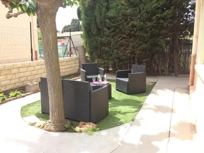 a group of chairs sitting next to a tree at Chouette coquette in Salses-le-Chateau