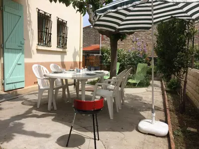 a white table and chairs under an umbrella at Chouette coquette in Salses-le-Chateau