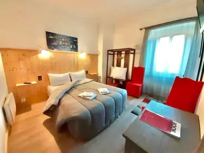 a bedroom with a large bed and a red chair at Hotel Bayle in Belcaire