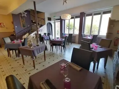 a dining room with tables and chairs and windows at Hotel Bayle in Belcaire