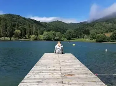 a person sitting on a dock in the water at Hotel Bayle in Belcaire