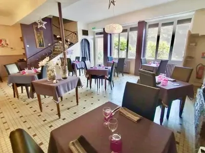 a dining room with tables and chairs in a restaurant at Hotel Bayle in Belcaire