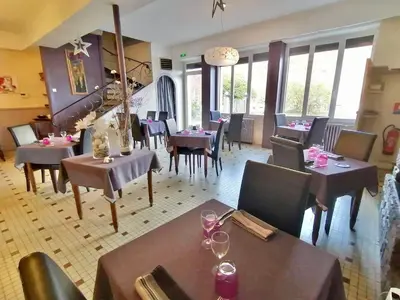 a dining room with tables and chairs and windows at Hotel Bayle in Belcaire