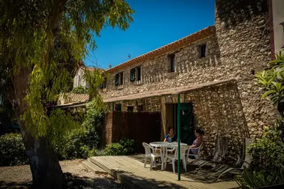 a woman sitting at a table outside of a building at Les Fenals in Fitou