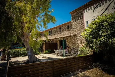 a woman sitting at a table in front of a house at Les Fenals in Fitou