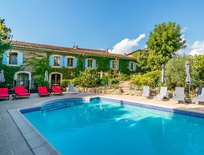 a pool in front of a house with red chairs at Eloi Merle - Chambre d'hôtes in Olonzac