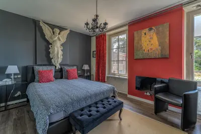 a bedroom with a bed and a red wall at Le Clos des Troubadours in Pennautier