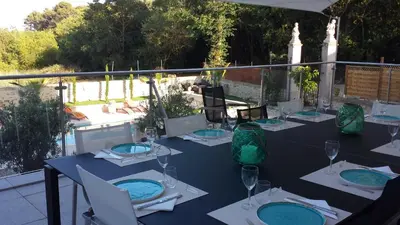 a table with plates and wine glasses on a balcony at Le Clos des Troubadours in Pennautier