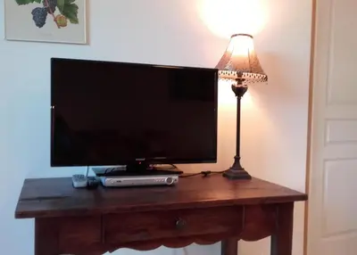 a flat screen tv sitting on a table with a lamp at gîtes 
