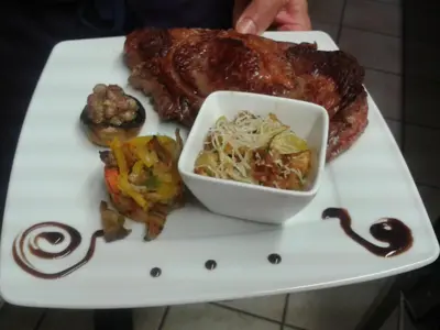 a plate of food with steak and a bowl of coleslaw at Le Baudilois in Pont-de-Larn