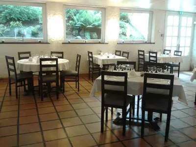a dining room with white tables and chairs and windows at Le Baudilois in Pont-de-Larn
