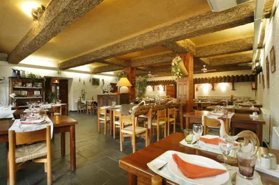 a restaurant with wooden tables and chairs and a dining room at Logis Hôtel Cartier in Quillan