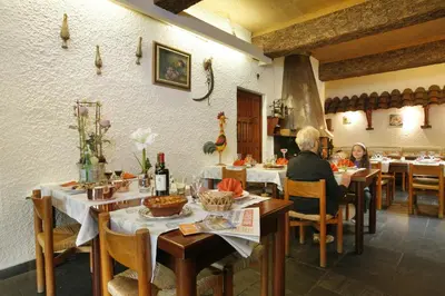 a man and woman sitting at tables in a restaurant at Logis Hôtel Cartier in Quillan