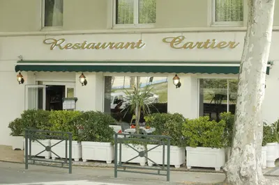 a restaurant with a green awning in front of a building at Logis Hôtel Cartier in Quillan