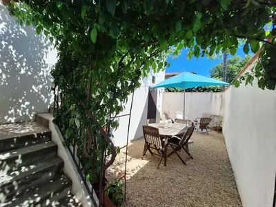 a table with a blue umbrella on a patio at Les Gîtes de Nathalie: Corneille et Rivals in Carcassonne