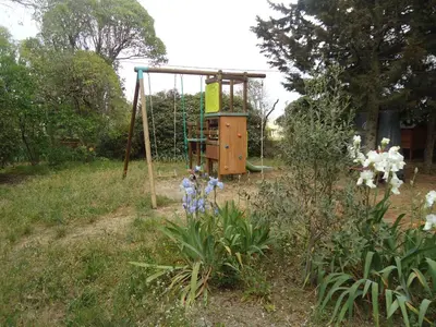 a playground in a garden with a swing at Domaine de la Pinsonnière in La Livinière