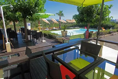 a resort with a swimming pool and a table and chairs at Logis Hôtel LE PRESSOIR in Saint-Chinian