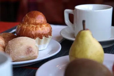 a table with plates of muffins and a pear and a cup of coffee at Logis Hôtel LE PRESSOIR in Saint-Chinian