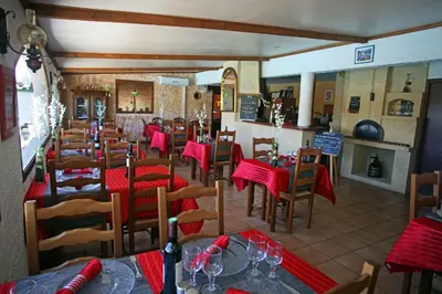 a restaurant with tables and chairs with red table cloth at Logis Hôtel LE PRESSOIR in Saint-Chinian
