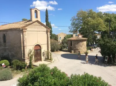 an old building with a church in a village at Le Neptune in Le Somail