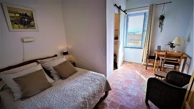 a bedroom with a bed and a table and a chair at Le Neptune in Le Somail
