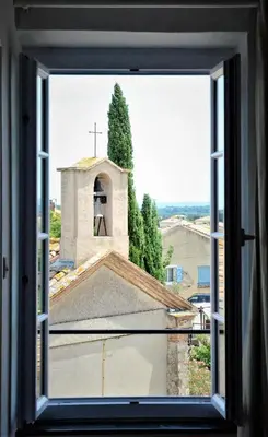 a window view of a church with a bell tower at Le Neptune in Le Somail