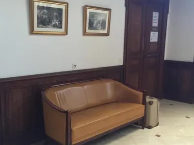 a leather bench in a room with two pictures on the wall at Le Jardin d'Homps in Homps