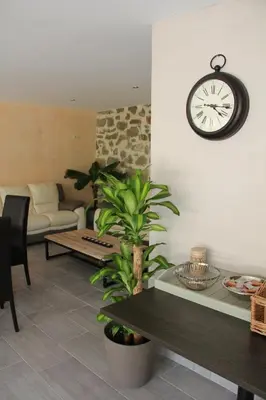 a living room with a table and a clock on the wall at Les Jardins de Soulane B&B - Adults only in Belcastel-et-Buc