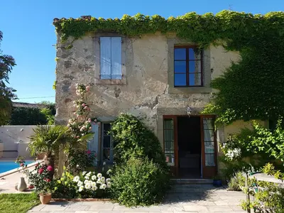 a stone house with flowers on the side of it at The Cottage, Clos des Archers in Aigues-Vives