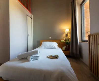 a bedroom with a large white bed with a plate on it at Domaine de Garabaud in Mazères