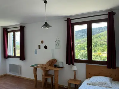 a bedroom with a bed and a desk and windows at Mas Lluganas in Mosset