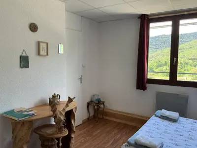 a room with a desk and a bed and a window at Mas Lluganas in Mosset