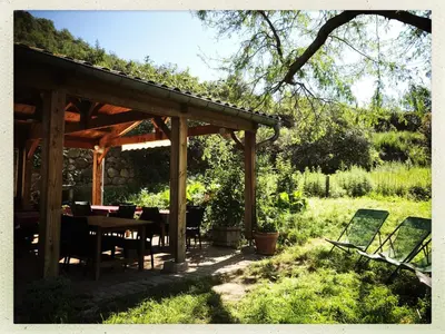 a wooden pavilion with a table and chairs in a garden at Mas Lluganas in Mosset