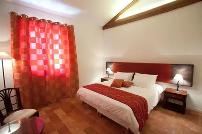 a bedroom with a bed and a red curtain at Gîtes la Vernède in Nissan-lez-Enserune