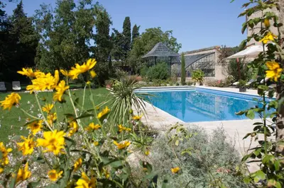 a garden with yellow flowers next to a swimming pool at Gîtes la Vernède in Nissan-lez-Enserune
