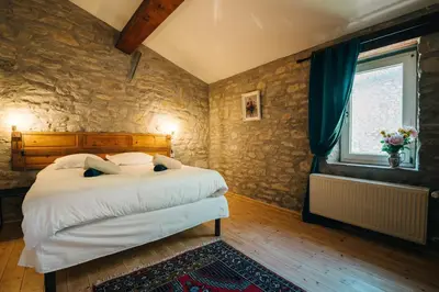 a bedroom with a bed and a stone wall at Domaine Calmel & Joseph in Montirat