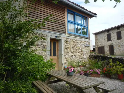 a wooden picnic table in front of a stone house at Gite Sent Martin in Roquefixade