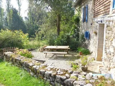 a picnic table in a garden next to a stone wall at Gite Sent Martin in Roquefixade