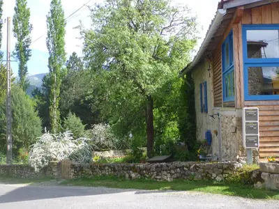 a house with a stone wall and a tree at Gite Sent Martin in Roquefixade
