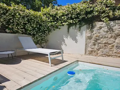 a chair sitting on a deck next to a swimming pool at Chez Lola-Maison d'hôtes Corbières in Durban-Corbières