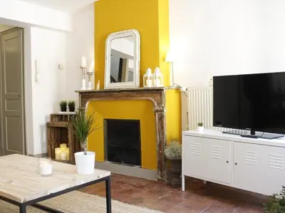 a living room with a television and a fireplace at Le Relais de la Maison Bacou in Carcassonne