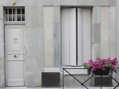 a building with two doors and a flower pot with purple flowers at Le Relais de la Maison Bacou in Carcassonne
