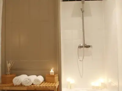 a bathroom with a shower with towels and a candle at Le Relais de la Maison Bacou in Carcassonne