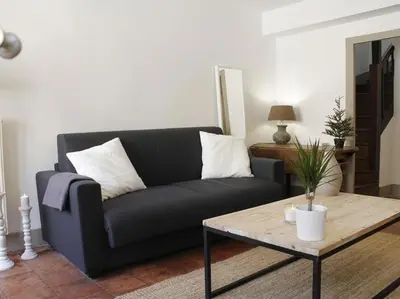 a living room with a black couch and a coffee table at Le Relais de la Maison Bacou in Carcassonne