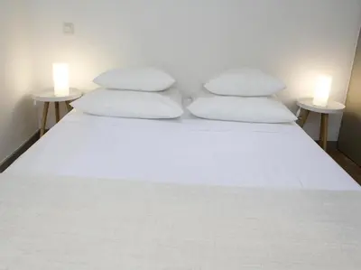 a bed with two white pillows and two tables at Le Relais de la Maison Bacou in Carcassonne