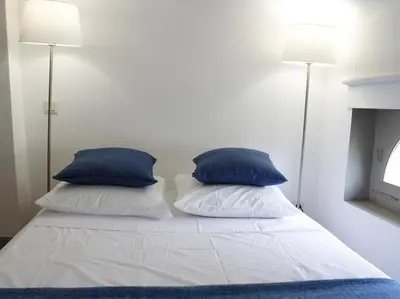 a bed with two blue pillows on top of it at Le Relais de la Maison Bacou in Carcassonne