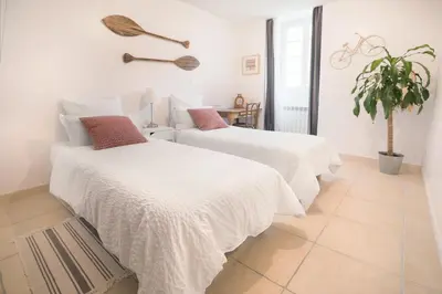 two beds in a white room with a potted plant at H2o Chambres d'Hôtes in Peyriac-de-Mer