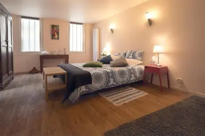 a bedroom with a bed and a table and two windows at H2o Chambres d'Hôtes in Peyriac-de-Mer