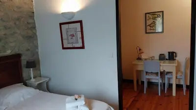 a bedroom with a table and a bed and a table and chairs at L'Envolée in Belvianes-et-Cavirac