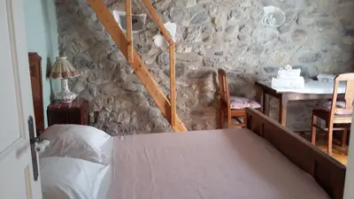 a bedroom with a bed and a stone wall at L'Envolée in Belvianes-et-Cavirac